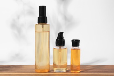 Bottles with cosmetic products on wooden table against white background