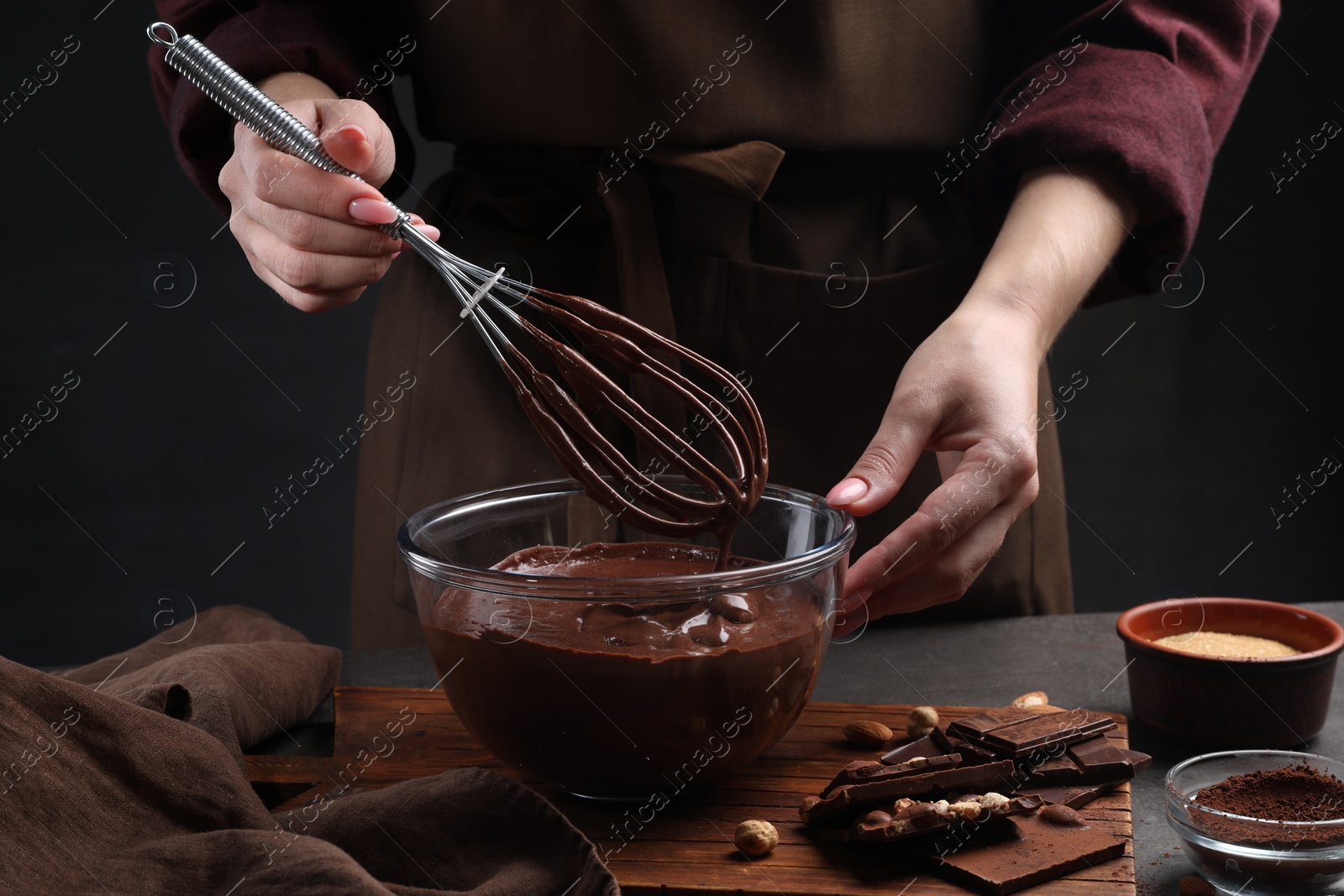 Photo of Woman with whisk mixing delicious chocolate cream at table, closeup