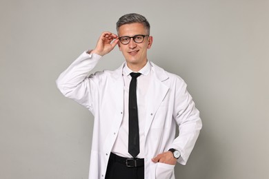 Photo of Happy doctor in glasses on grey background