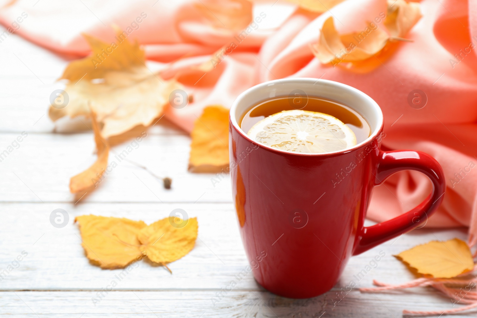 Photo of Cup of hot drink and leaves on white wooden table. Cozy autumn atmosphere