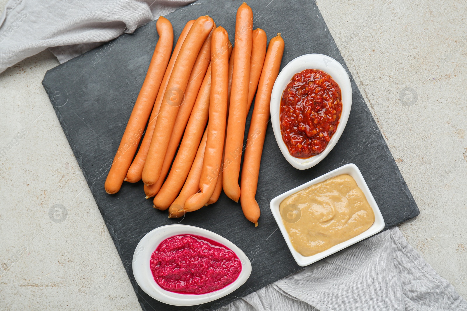 Photo of Delicious sausages, ketchup, mustard and horseradish on grey table, flat lay