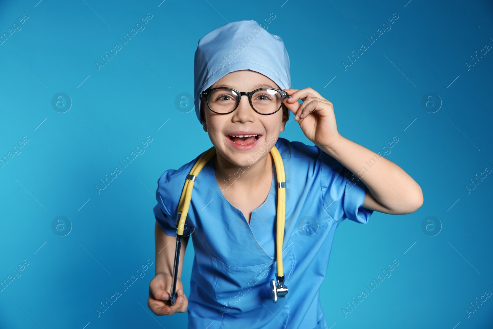 Photo of Cute little child in doctor uniform with stethoscope on color background