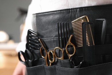 Photo of Hairstylist with professional tools in waist pouch in salon, closeup