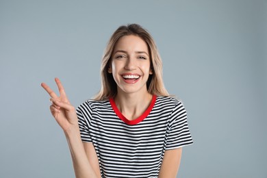 Photo of Woman showing number two with her hand on light grey background