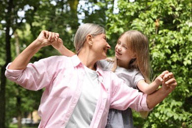 Photo of Happy grandmother with her granddaughter spending time together outdoors