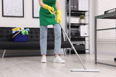 Photo of Cleaning service worker washing floor with mop in office, closeup