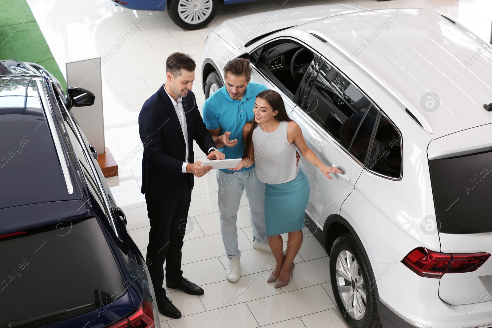 Photo of Salesman consulting young couple in car salon