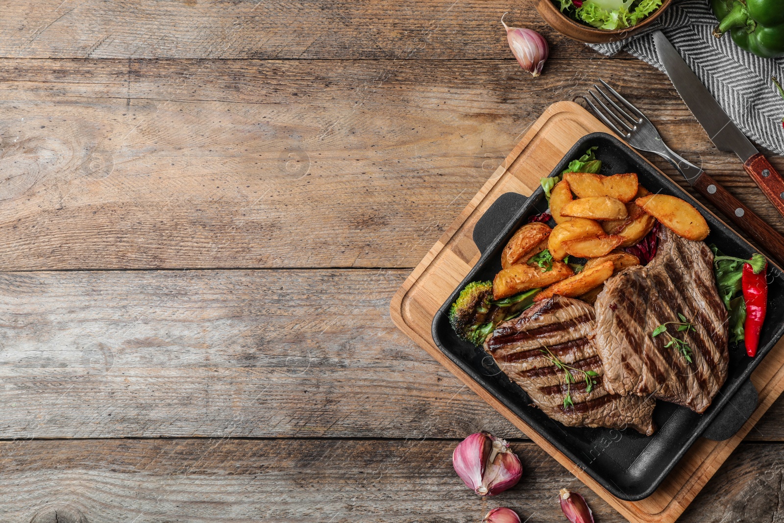 Photo of Delicious beef steaks served on wooden table, flat lay. Space for text