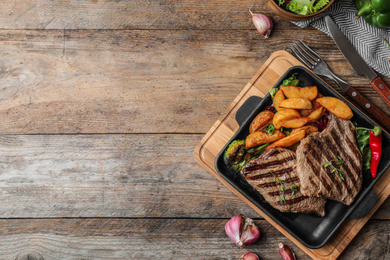Photo of Delicious beef steaks served on wooden table, flat lay. Space for text