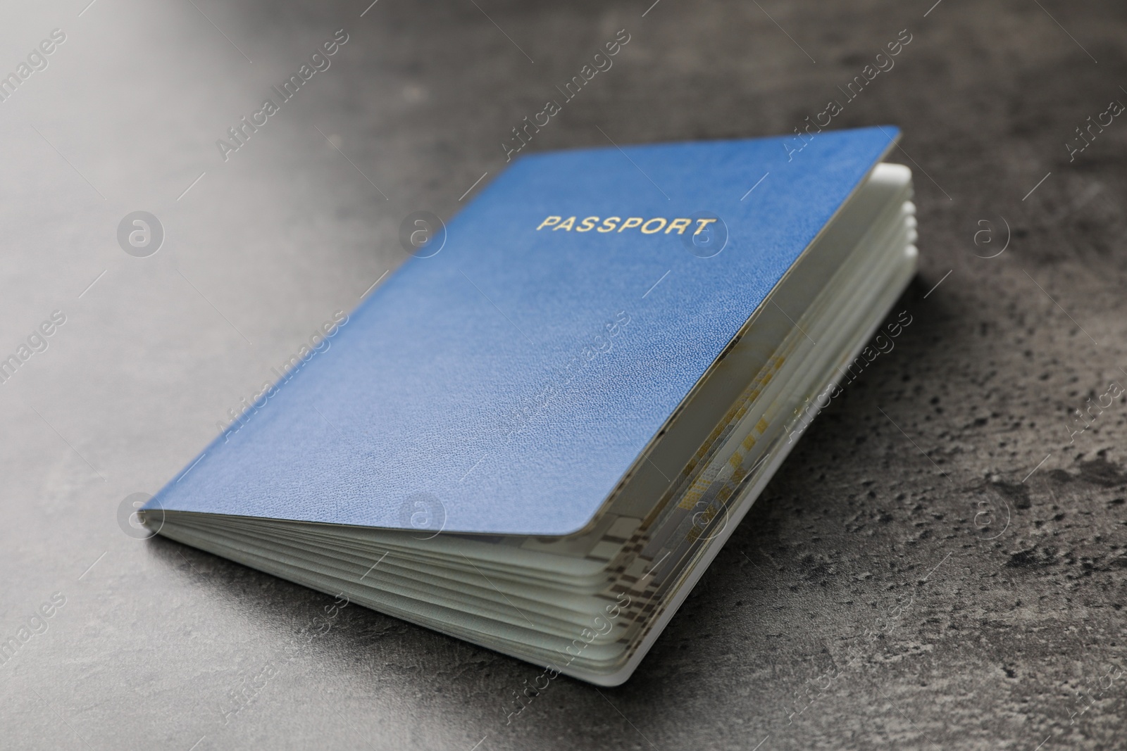 Photo of Blank blue passport on dark grey table, closeup