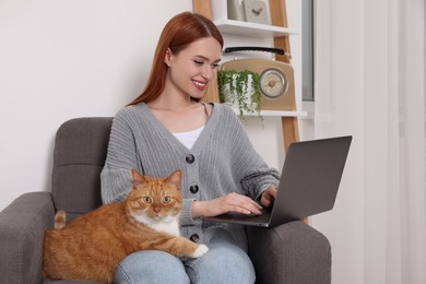 Happy woman with cat working in armchair at home