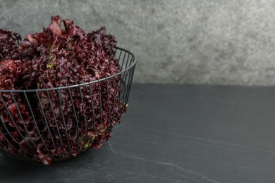 Photo of Metal bowl with red coral lettuce on grey table. Space for text