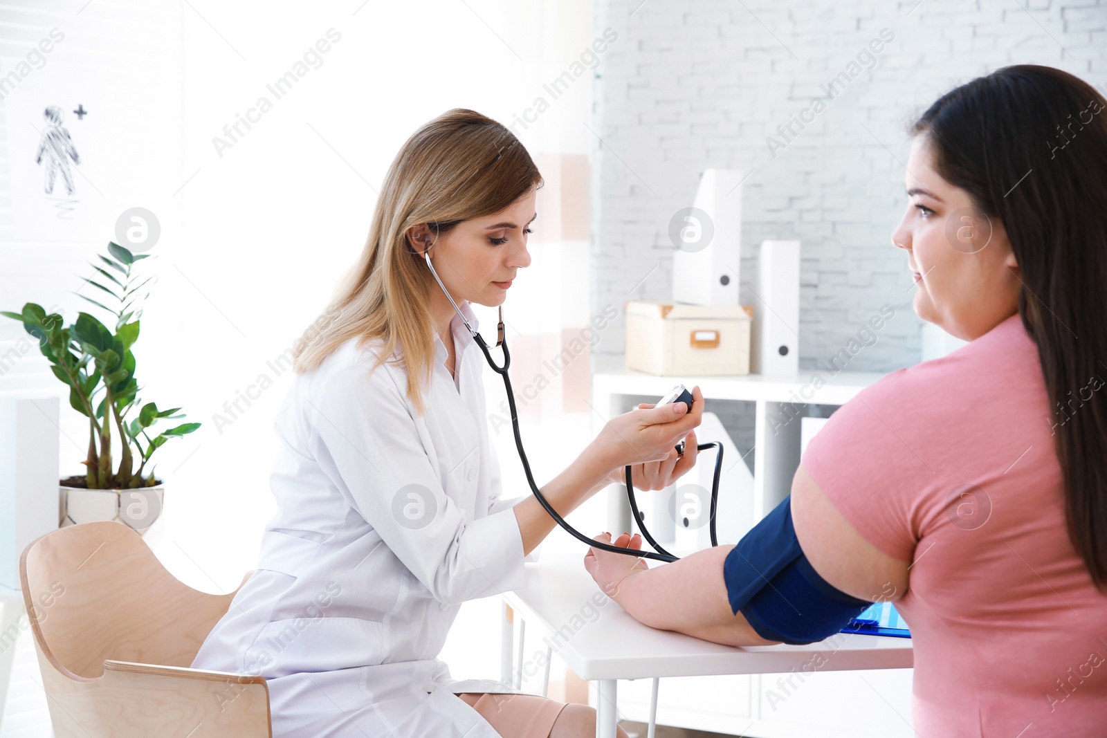 Photo of Female doctor measuring blood pressure of overweight woman in clinic