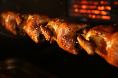 Photo of Grilling whole chickens in rotisserie machine, closeup
