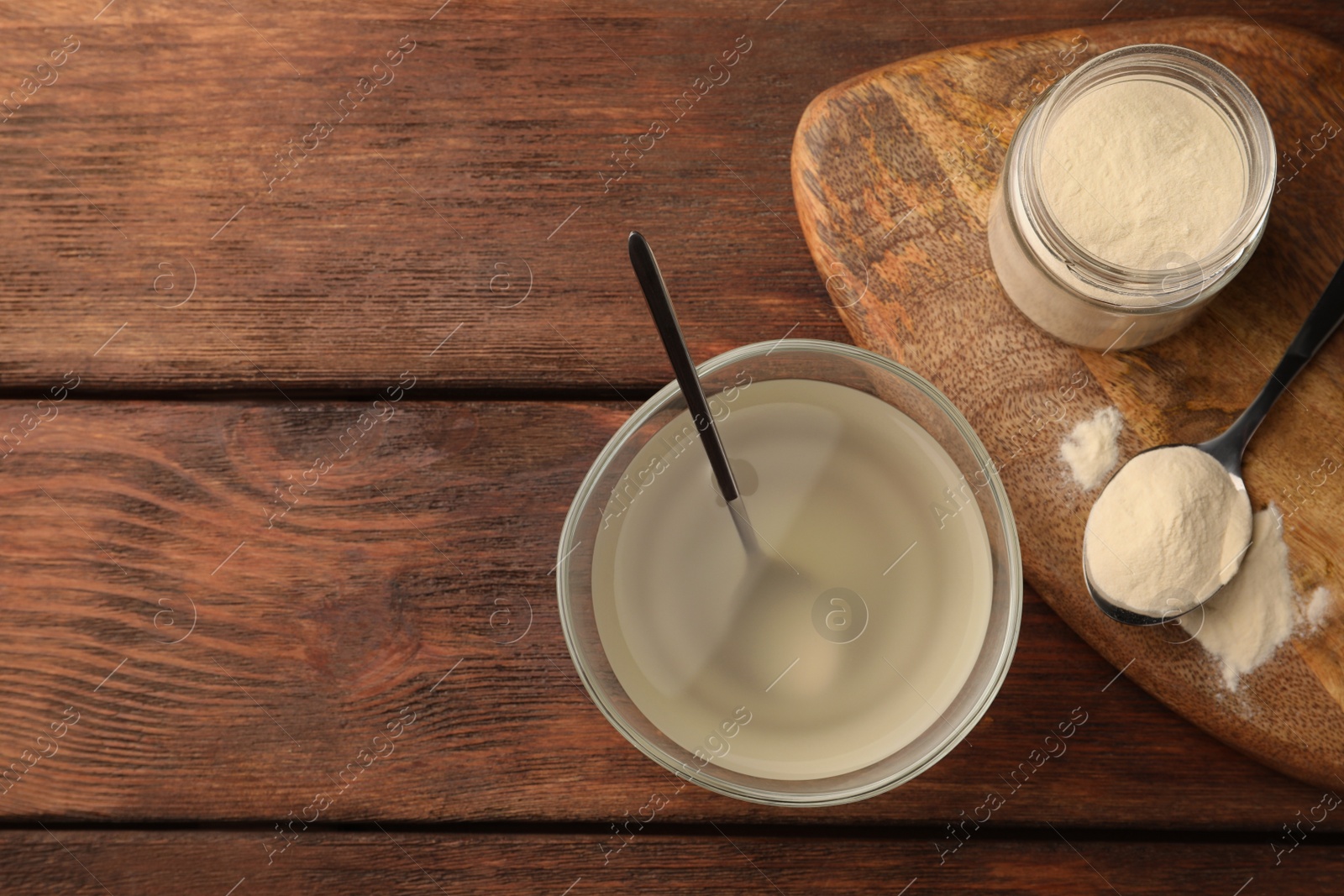 Photo of Glass bowl of agar-agar jelly and powder on wooden table, flat lay. Space for text