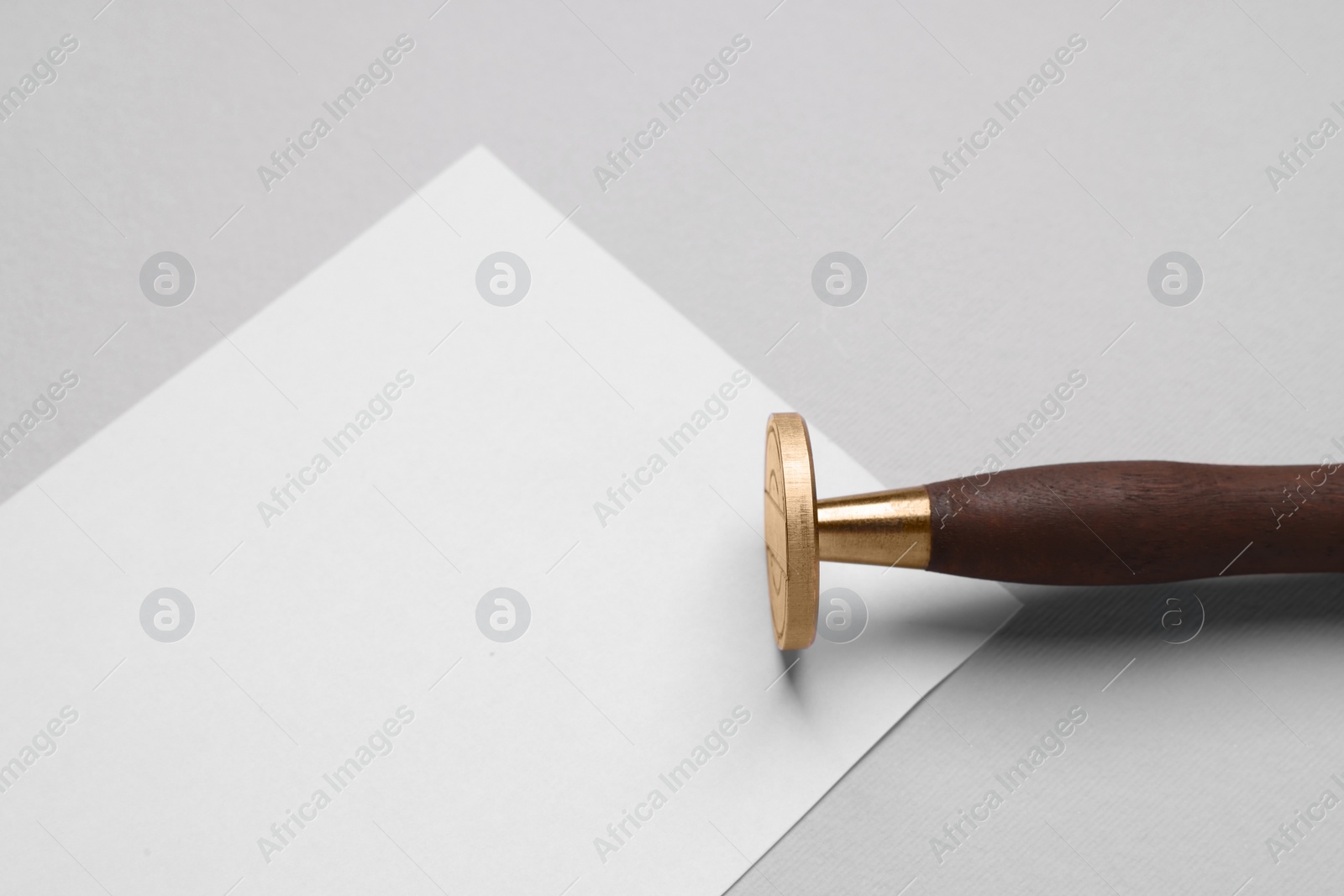 Photo of One stamp tool and sheet of paper on light grey background, closeup. Space for text