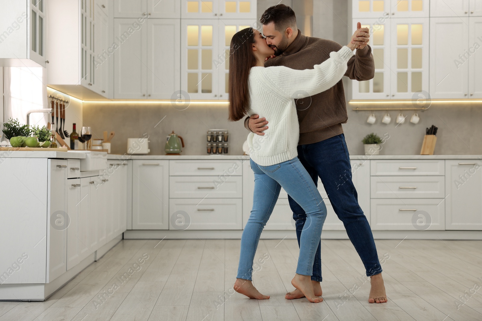 Photo of Affectionate young couple dancing and kissing in kitchen. Space for text