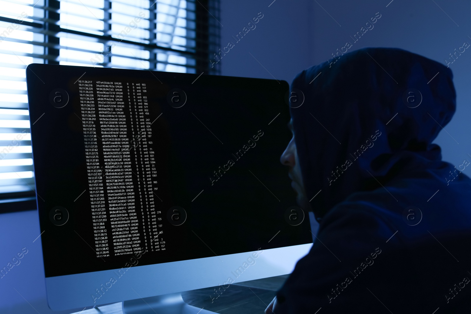 Photo of Man using computer in dark room. Criminal offence