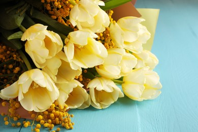 Bouquet with beautiful tulips and mimosa flowers on light blue wooden table