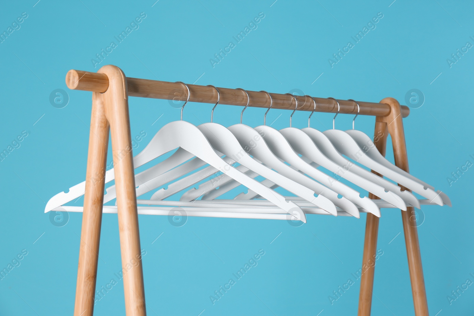 Photo of Wooden rack with clothes hangers on color background