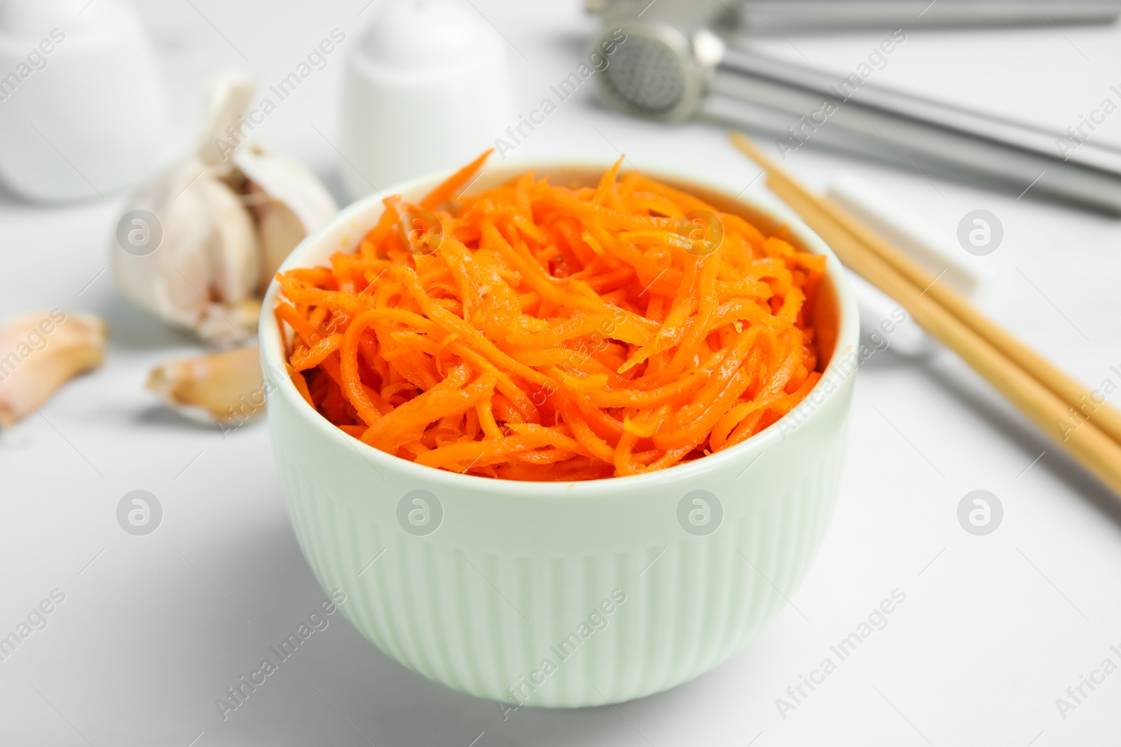 Photo of Delicious Korean carrot salad in bowl on white table