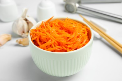 Photo of Delicious Korean carrot salad in bowl on white table