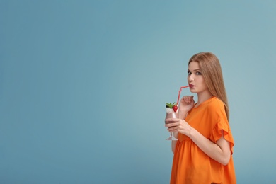 Photo of Young woman with glass of delicious milk shake on color background