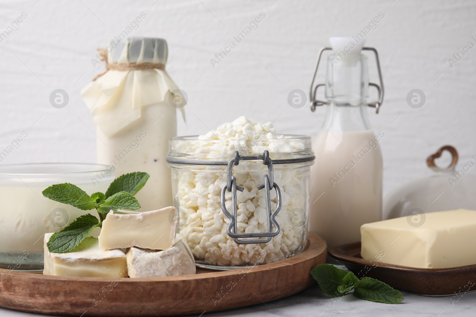 Photo of Different dairy products and mint on white marble table