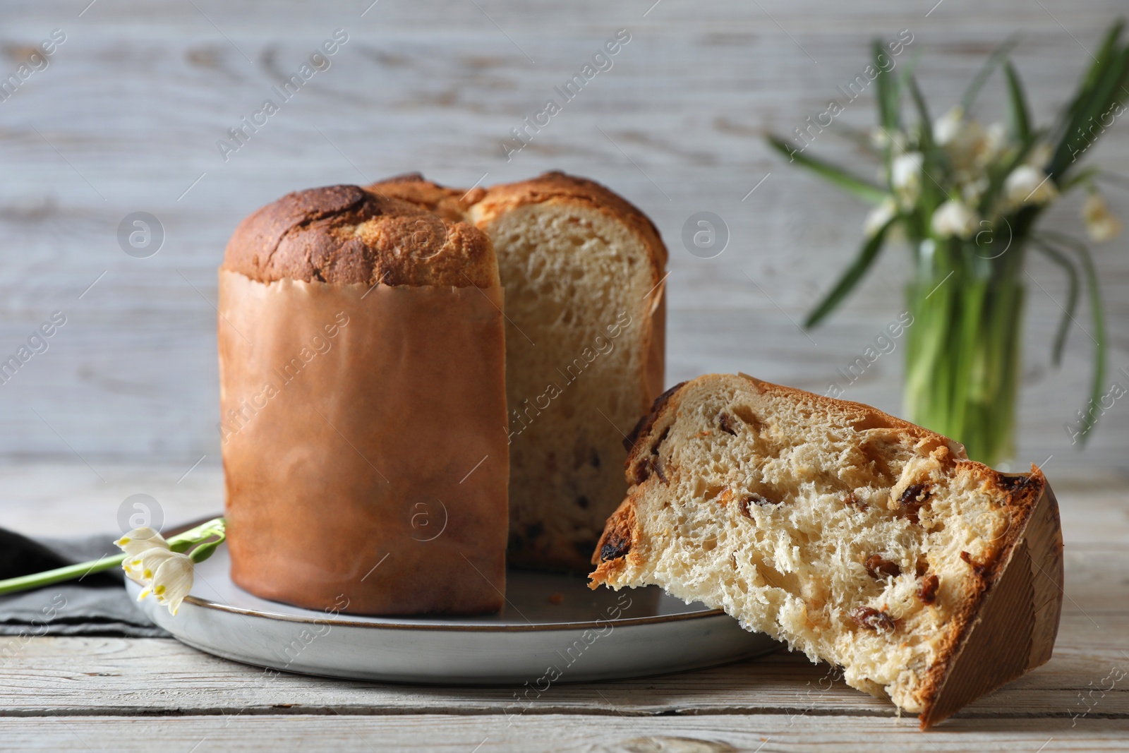 Photo of Delicious cut Panettone cake on light wooden table. Traditional Italian pastry