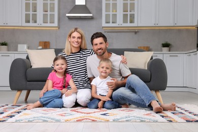 Portrait of happy family with children on soft rug at home