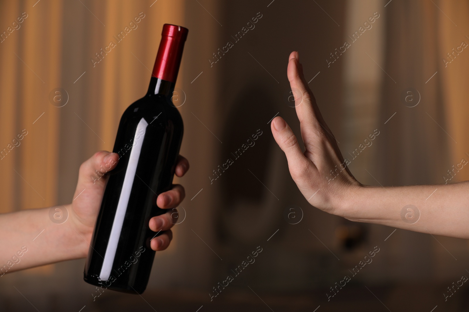 Photo of Woman refusing to drink red wine indoors, closeup. Alcohol addiction treatment