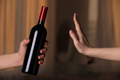 Photo of Woman refusing to drink red wine indoors, closeup. Alcohol addiction treatment