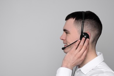 Photo of Hotline operator with headset on light grey background, space for text