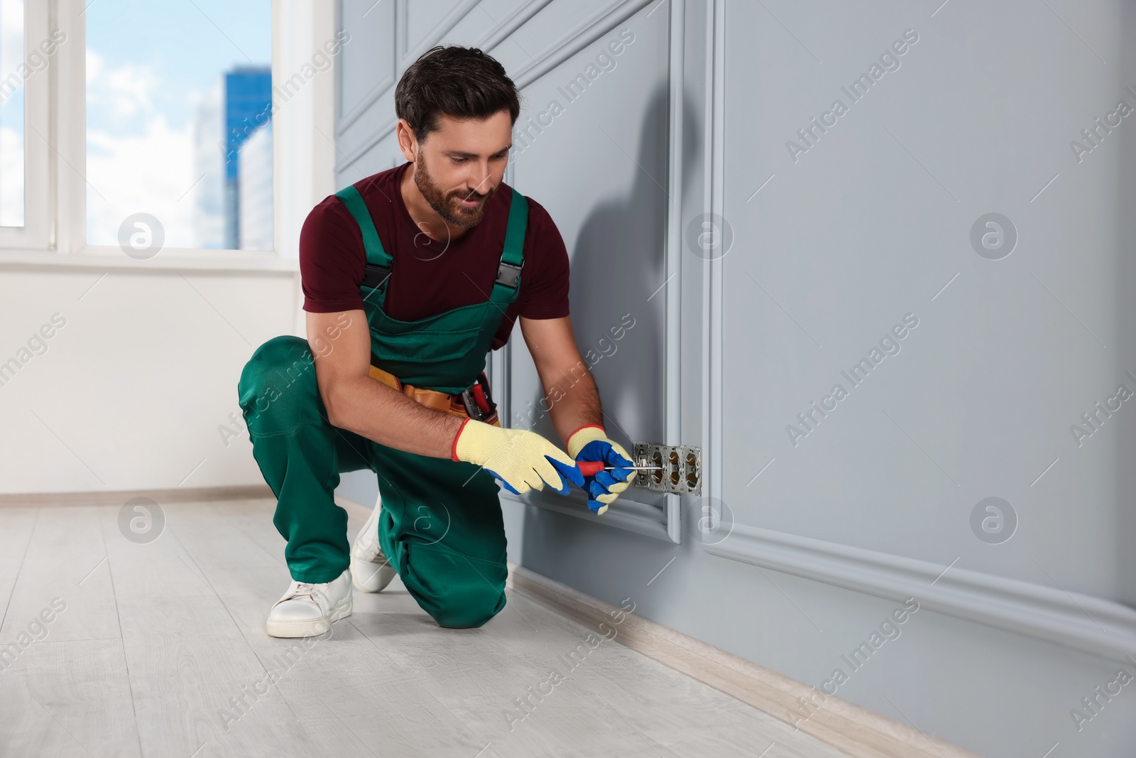 Photo of Electrician with screwdriver repairing power sockets indoors