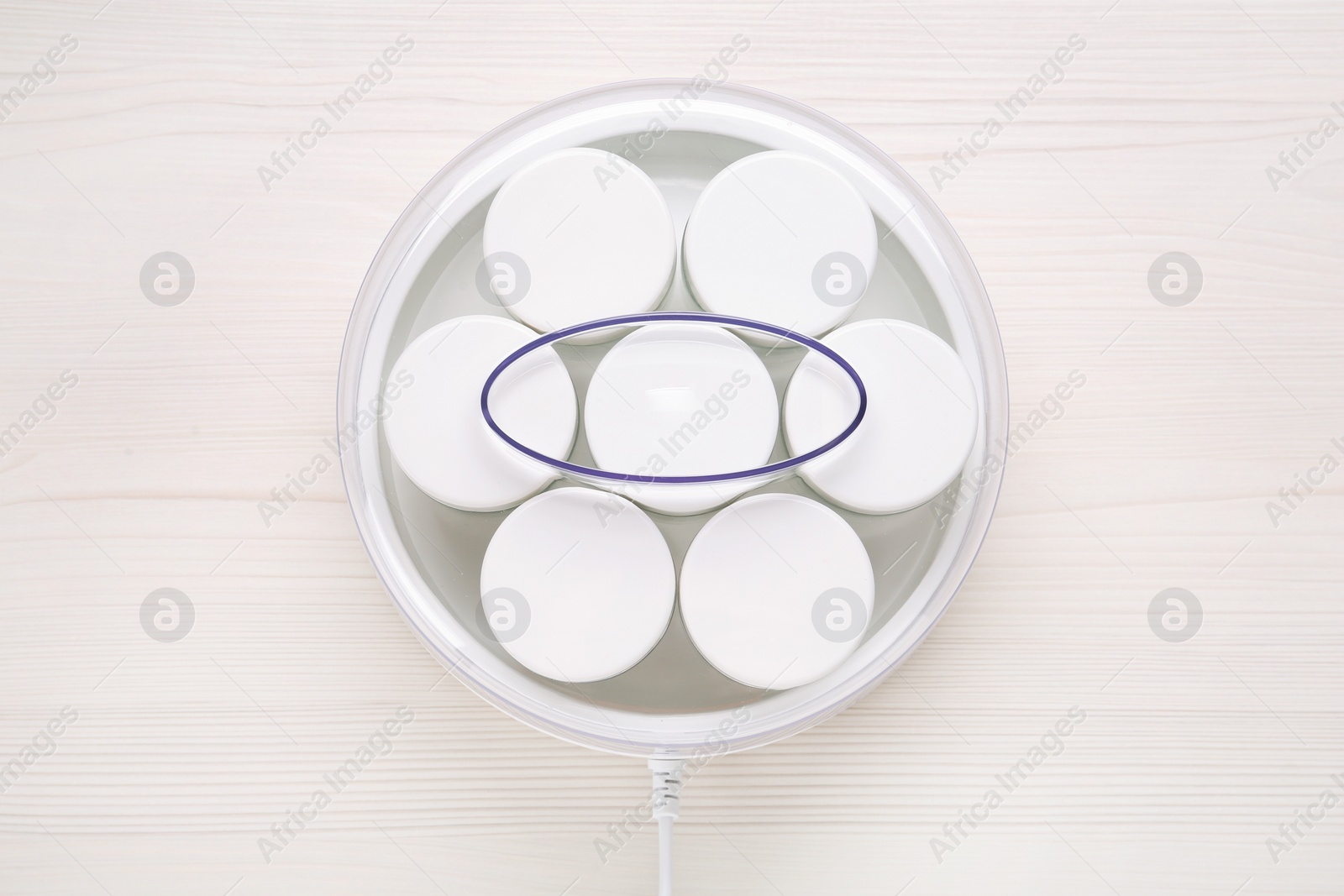 Photo of Modern yogurt maker with jars on white wooden table, top view