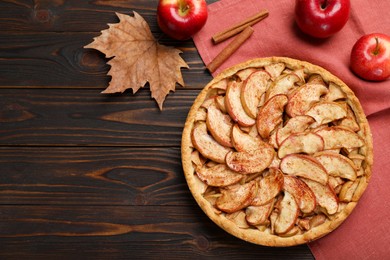 Photo of Delicious apple pie, fresh fruits and cinnamon on wooden table, flat lay. Space for text