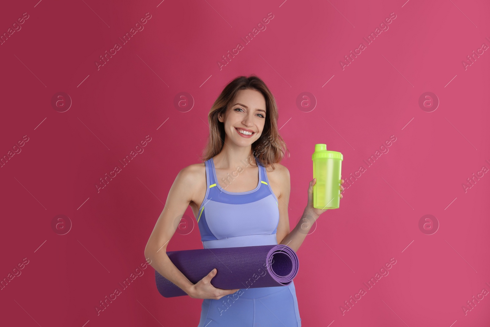 Photo of Beautiful woman with yoga mat and shaker on pink background