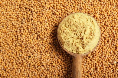 Photo of Wooden spoon of aromatic mustard powder on seeds, top view. Space for text