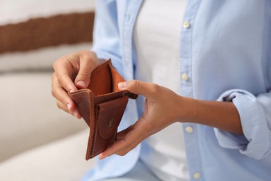 Woman with empty wallet indoors, closeup. Debt problem