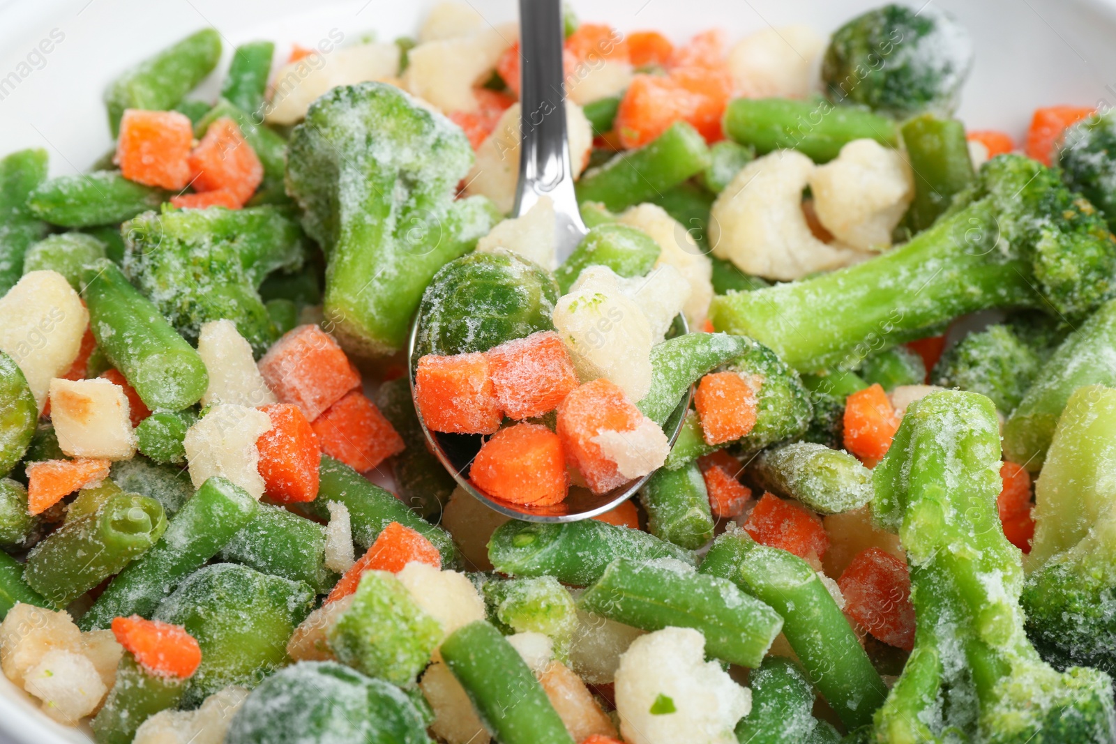 Photo of Mix of frozen vegetables and spoon, closeup