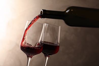 Photo of Pouring wine from bottle into glass on color background