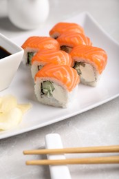 Photo of Tasty sushi rolls, ginger and chopsticks on grey table, closeup