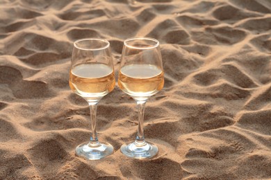 Photo of Glassestasty wine on sand, space for text