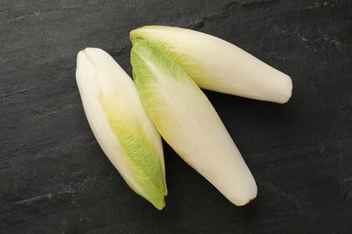 Fresh raw Belgian endives (chicory) on black table, top view