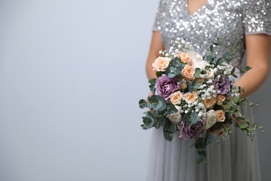 Photo of Bride holding beautiful wedding bouquet on light grey background, closeup. Space for text