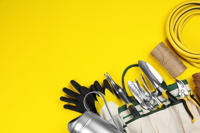 Flat lay composition with gardening tools on yellow background, space for text