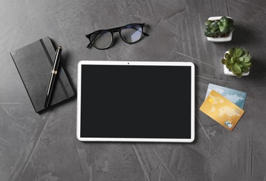 Online store. Tablet, stationery, glasses, credit cards and houseplants on grey table, flat lay