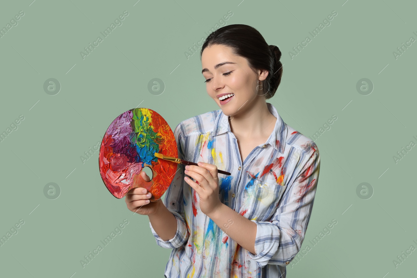 Photo of Woman with painting tools on pale green background. Young artist