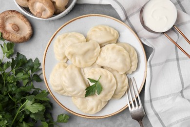 Delicious dumplings (varenyky) with mushrooms and parsley served on light grey table, flat lay