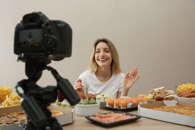 Photo of Food blogger recording eating show on camera against beige background. Mukbang vlog